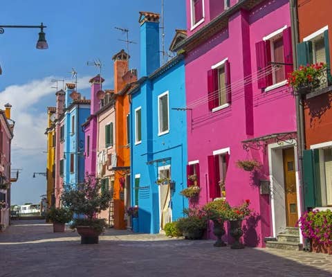 Case colorate di Burano, con cielo azzurro sullo sfondo, fotografate in una giornata serena.
