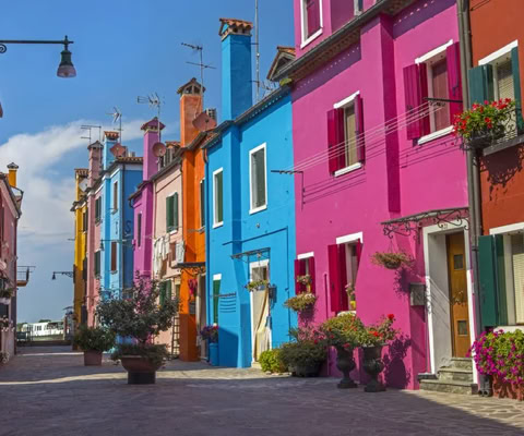 Case colorate di Burano, con cielo azzurro sullo sfondo, fotografate in una giornata serena.