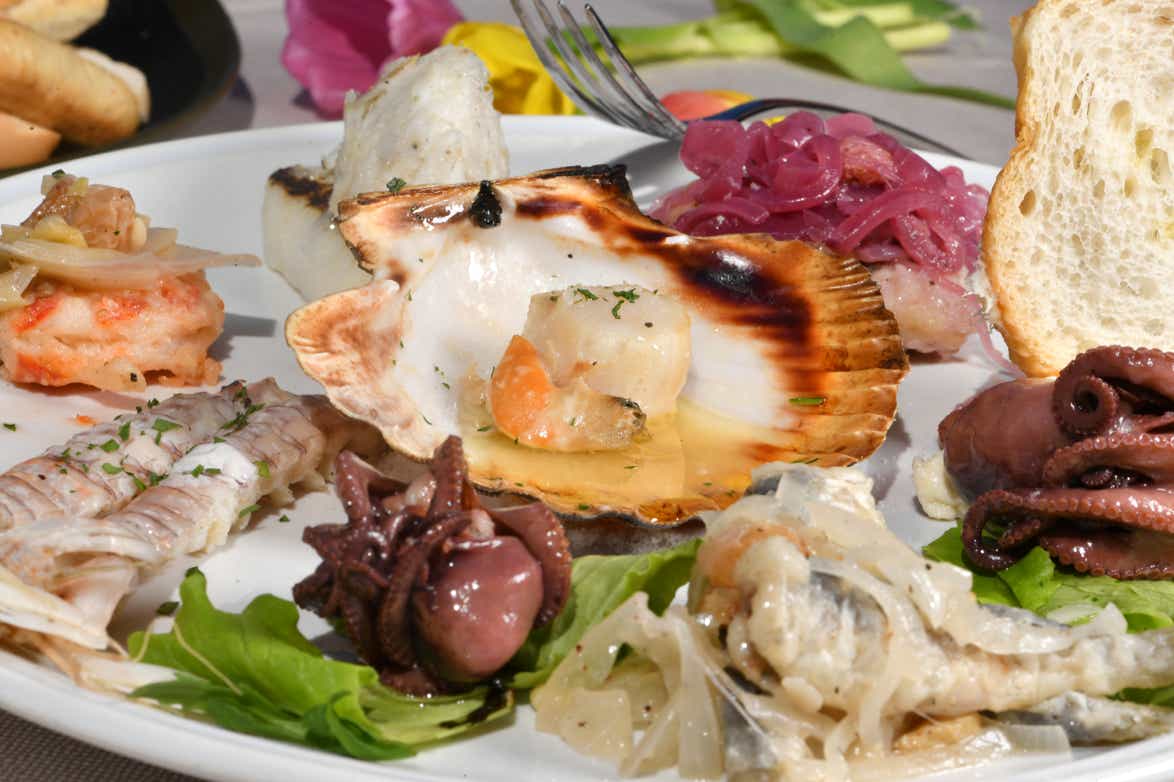 Dettaglio di un piatto di antipasto misto di pesce alla Veneziana, con capa santa, folpetto, canocchie, scampi in saor, sarde in saor e baccalà mantecato con crostino di pane