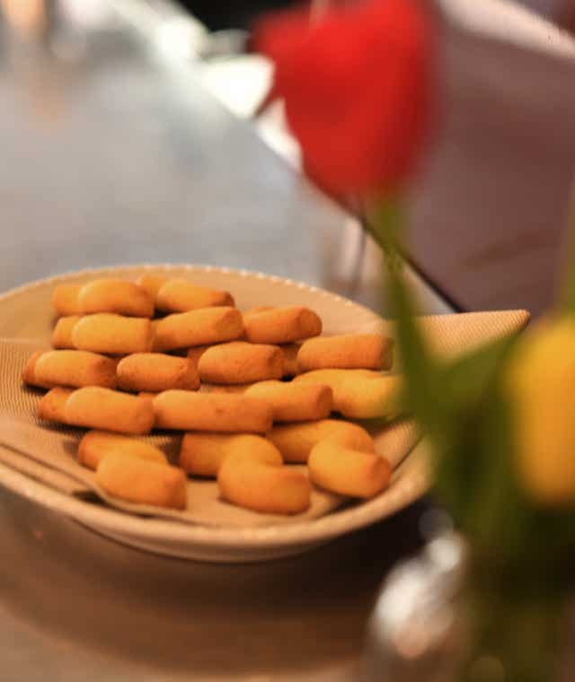 Dettaglio con un piatto di tradizionali biscotti buranelli, serviti su un piatto sul bancone.