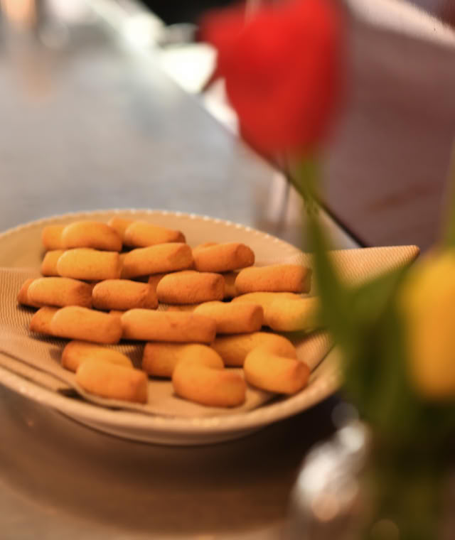 Dettaglio con un piatto di tradizionali biscotti buranelli, serviti su un piatto sul bancone.