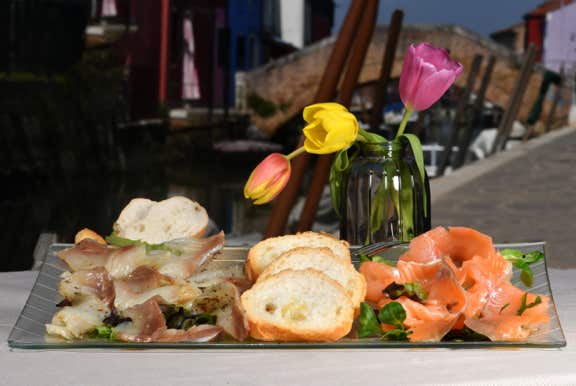 Piatto con bis di marinati con salmone e ricciòla serviti con crostini di pane